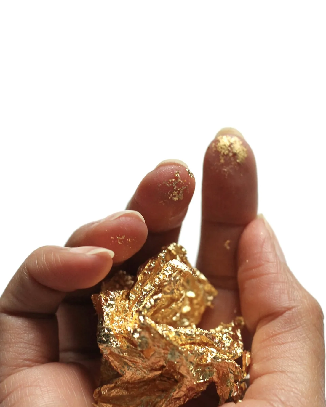 Hojas de pan de oro superpuestas, con pliegues y reflejos cálidos sobre fondo oscuro